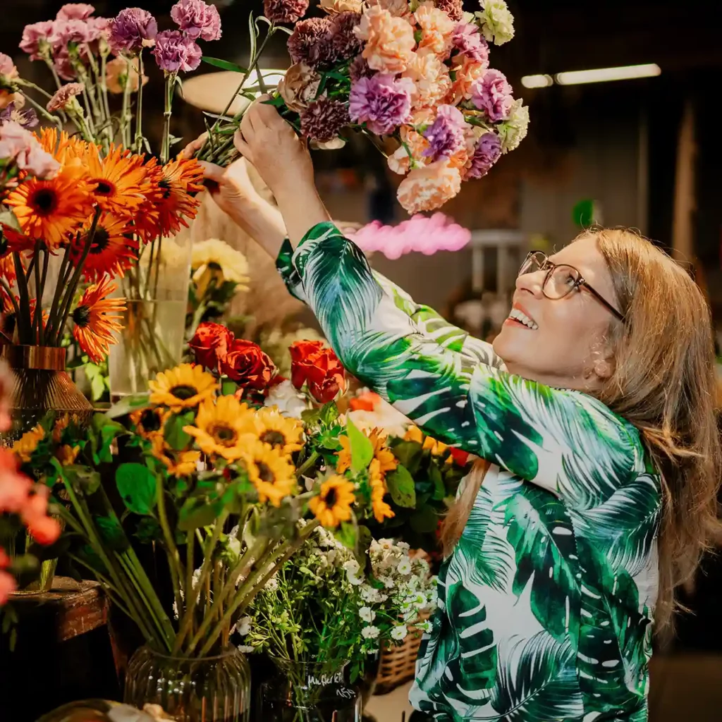 Blumenladen mit leuchtenden Sommerblumen. Floristin stellt einen Strauß zusammen.